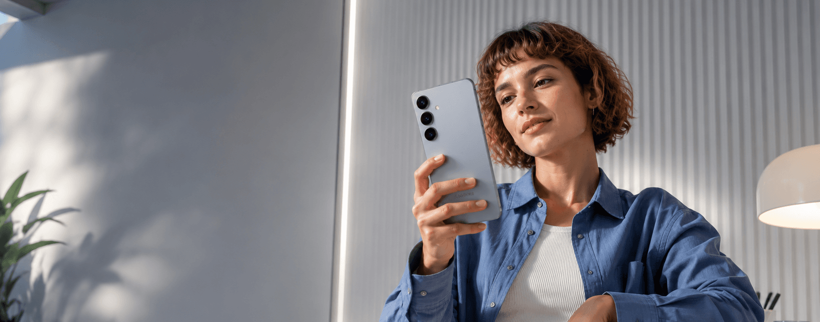 Девушка использует Samsung Galaxy S25 в современном интерьере — флагманский смартфон Samsung с Galaxy AI